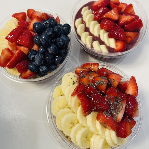 Three Krave Juice Bar acai bowls topped with fresh strawberries, bananas, blueberries, and chia seeds.
