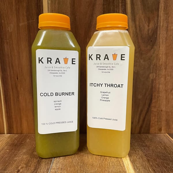 Two Krave Juice Bar cold-pressed juices, "Cold Burner" and "Itchy Throat," on a wooden surface.