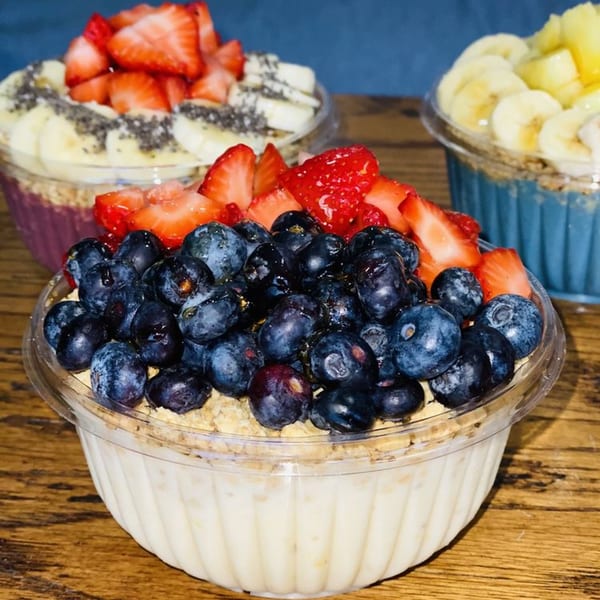 Three Krave Juice Bar acai bowls with fresh fruit toppings, including blueberries, strawberries, and bananas.