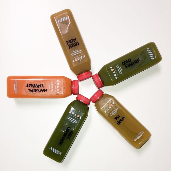 Five Krave Juice Bar bottles, filled with colorful juices, arranged in a star shape.