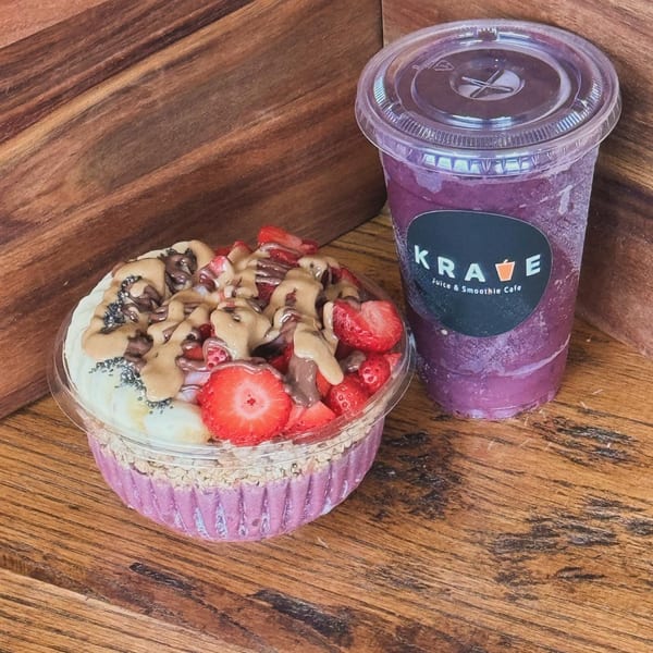 Krave Juice Bar's acai bowl with fruit, granola, and nut butter, next to a Krave smoothie.